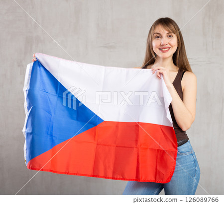 Happy young woman holding flag of Czech Republic against unicoloured 126089766