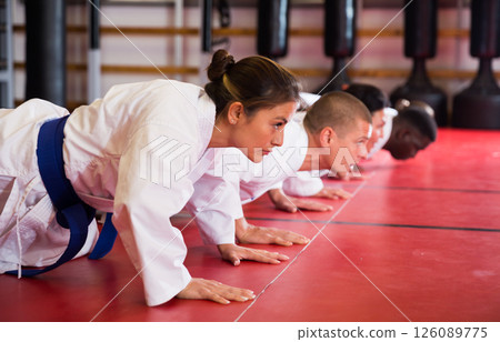 Multiracial group of men and women doing push-ups in gym Multiracial group of men and women doing push-ups in gym 126089775