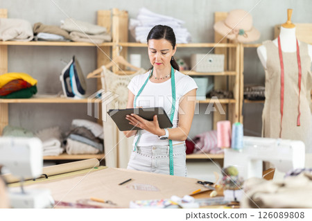 Woman tailor uses tablet when creating drawing of future product Woman tailor uses tablet when creating drawing of future product 126089808