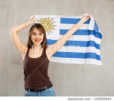 Young cheerful woman holding Uruguay flag Young cheerful woman holding Uruguay flag 126089844
