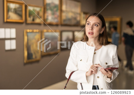 Woman in a Jacket and with a Phone in a Museum of Paintings 126089923