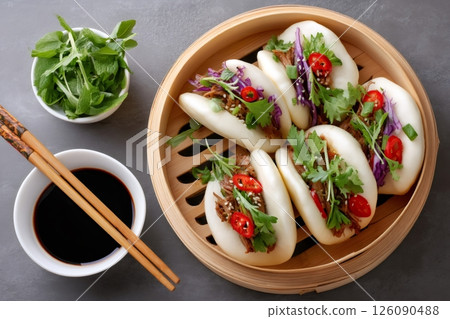 Steamed bao buns filled with braised pork belly, fresh herbs and chili pepper flakes in bamboo steamer 126090488