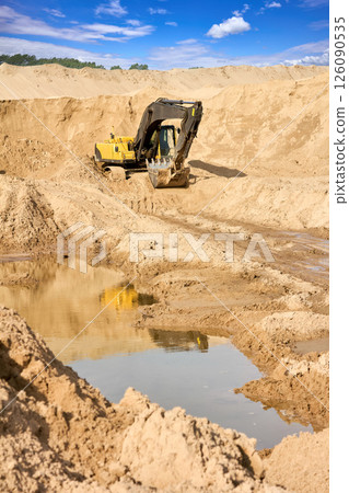 Heavy Excavator Digging Sand at Construction Site Under Blue Sky Heavy Excavator Digging Sand at Construction Site Under Blue Sky 126090535