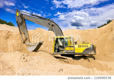 Heavy Excavator Digging Sand at Construction Site Under Blue Sky 126090536