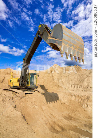 Heavy Excavator Digging Sand at Construction Site Under Blue Sky Heavy Excavator Digging Sand at Construction Site Under Blue Sky 126090537
