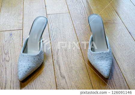 Pair of white sexy high heels mules on a natural wooden floor 126091146