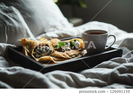 A cozy early morning scene with mini crepes filled with cashew cream, spinach, and fried mushrooms, placed on a rustic wooden tray. Fresh mint tea and soft sunlight complete the serene vibe A cozy early morning scene with mini crepes filled with cashew cream, spinach, and fried mushrooms, placed on a rustic wooden tray. Fresh mint tea and soft sunlight complete the serene vibe 126091150