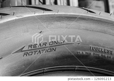 Close-up of the side of a new road motorcycle rear tire with the direction of rotation indicated Close-up of the side of a new road motorcycle rear tire with the direction of rotation indicated 126091213