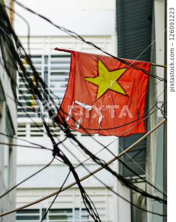 A tattered Vietnamese flag with in a tangle of electrical wires, a street scene in Ho Chi Minh City 126091223