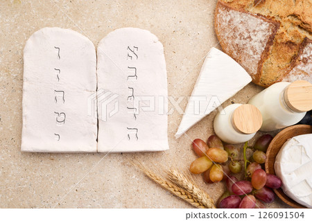 Happy Shavuot concept. Two Stones with Ten Commandments in Ancient Hebrew, Grains, milk and cheese Happy Shavuot concept. Two Stones with Ten Commandments in Ancient Hebrew, Grains, milk and cheese 126091504
