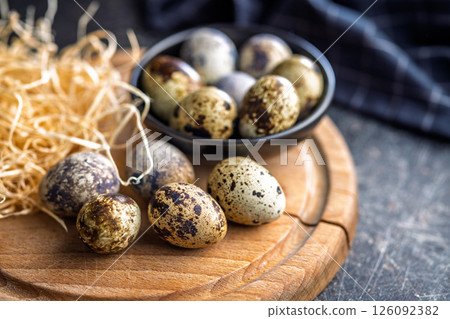 Spotted quail eggs on wooden cutting board on black table. 126092382