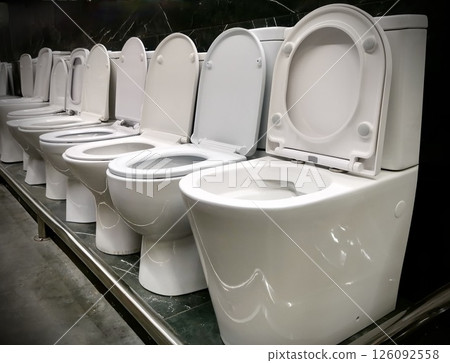 Modern white ceramic toilets displayed in a plumbing store showroom. Clean minimalist interior, suitable for construction, renovation, bathroom design 126092558