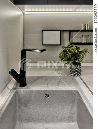 Modern kitchen interior with matte black faucet, metal sink and potted plant. Perfect for home design, eco-style and minimalism themes Modern kitchen interior with matte black faucet, metal sink and potted plant. Perfect for home design, eco-style and minimalism themes 126092559