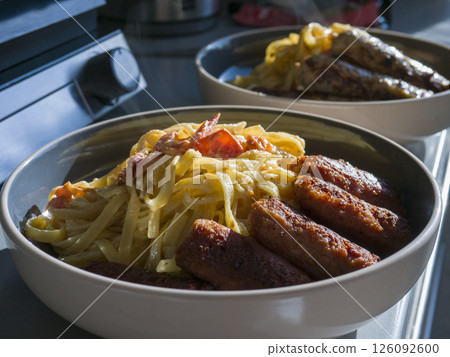 Pasta twirling with crispy bacon sausages, steaming in ceramic bowl, representing rich italian culinary comfort Pasta twirling with crispy bacon sausages, steaming in ceramic bowl, representing rich italian culinary comfort 126092600