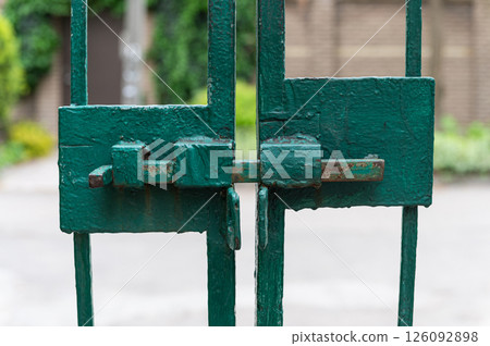 Close-up of rusty green metal gate with bolt lock. 126092898