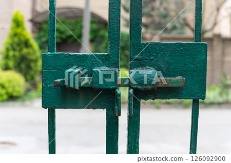 Close-up of rusty green metal gate with bolt lock. 126092900
