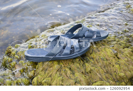 rubber flip flops on the seashore. shoes at the water's edge on the sea beach 126092954