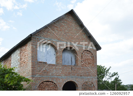 rural unfinished house. the windows are bricked up and clogged with plywood rural unfinished house. the windows are bricked up and clogged with plywood 126092957