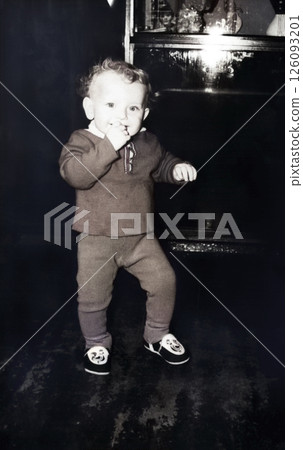 Vintage portrait of a curly little boy. The child is learning to walk. The boy is smiling. Retro photo from 1967. 126093201