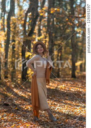Woman Autumn Forest Portrait: Smiling woman in beige outfit poses outdoors during autumn foliage, showcasing fall fashion in woodland setting. Woman Autumn Forest Portrait: Smiling woman in beige outfit poses outdoors during autumn foliage, showcasing fall fashion in woodland setting. 126093297
