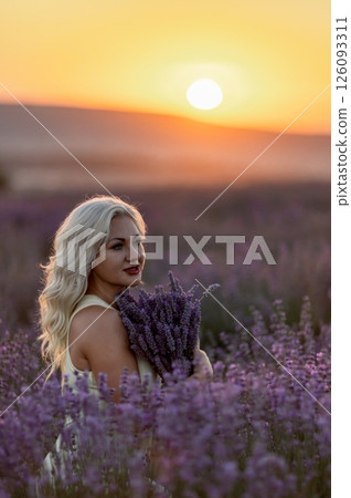 Blonde woman poses in lavender field at sunset. Happy woman in white dress holds lavender bouquet. Aromatherapy concept, lavender oil, photo session in lavender Blonde woman poses in lavender field at sunset. Happy woman in white dress holds lavender bouquet. Aromatherapy concept, lavender oil, photo session in lavender 126093311