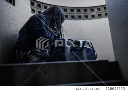 High school girl crouching on the landing of the stairs: Bullying, school refusal, anxiety about the future 126093333