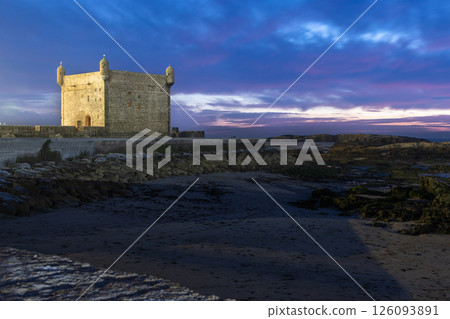Blue fishing boats in a harbor and Port of Essaouira Sqala, Portuguese castle in a sunset lights, Essaouira, Morocco 126093891