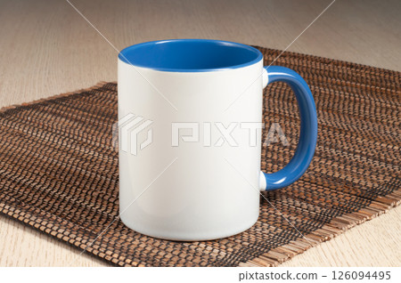 Two-tone 11oz mug on the straw mat on the table. Mug with bluehandle and inner part. Two-tone 11oz mug on the straw mat on the table. Mug with bluehandle and inner part. 126094495