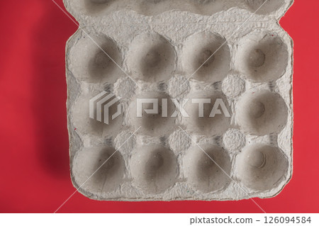 Reusable cardboard egg carton on a bright red background. Top view 126094584