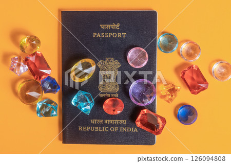 Indian passport surrounded by colorful gemstones on a bright orange surface 126094808