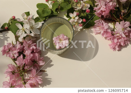 Glass of green matcha tea on beige table background in sunlight. Floral decor. Blooming apple, japanese cherry tree sakura branches in sunlight. Healthy life style. Copy space. Flat lay, top view. Glass of green matcha tea on beige table background in sunlight. Floral decor. Blooming apple, japanese cherry tree sakura branches in sunlight. Healthy life style. Copy space. Flat lay, top view. 126095714