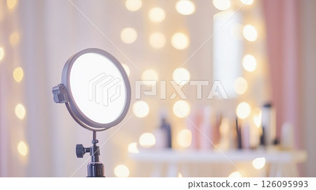 Illuminated ring light setup for cosmetic application with blurred beauty products. 126095993