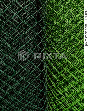 green wire mesh rolls create interesting pattern in crafting project during afternoon light. closeup green wire mesh rolls create interesting pattern in crafting project during afternoon light. closeup 126097195