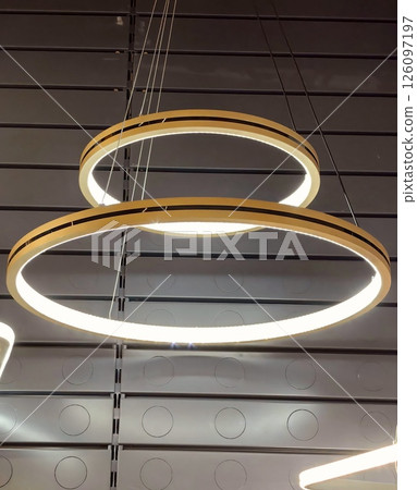 modern ring-shaped ceiling lights illuminate contemporary interior space during daylight hours. modern ring-shaped ceiling lights illuminate contemporary interior space during daylight hours. 126097197