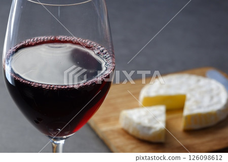 Relax with a glass of red wine and some Camembert cheese as a snack. 126098612