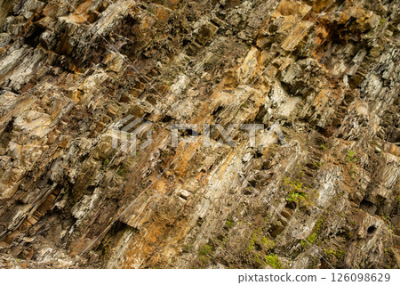 Stunning natural rock formation showcasing earthy tones and textures along a rugged cliffside in a serene landscape during daylight hours 126098629