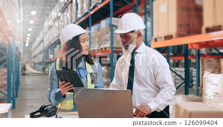 People, tablet or laptop at warehouse with logistics, meeting or discussion with supply chain management. Woman, mentor or talk with review, tech or planning for inventory at industrial storage plant 126099404