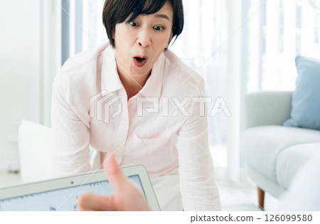 A middle-aged couple happily watching a computer in the living room 126099580