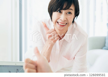 A middle-aged couple happily watching a computer in the living room A middle-aged couple happily watching a computer in the living room 126099581