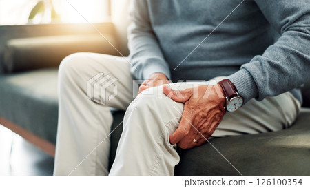 Hands, knee pain and old person on couch with injury, retirement and health issue with muscle tension at home. Fibromyalgia, arthritis or brittle bones with legs, inflammation and pressure in house 126100354
