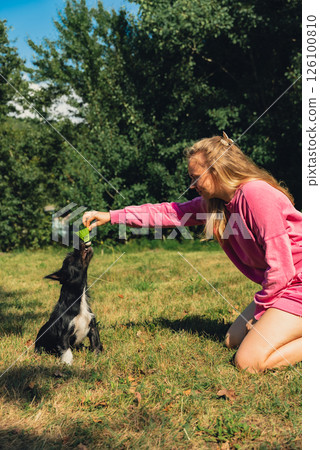 Woman spending quality time with her pet playing Badminton shuttlecock on green grass. Outside recreation and fresh air summertime. Healthy lifestyle nature connection sport summer activities. Stress 126100810