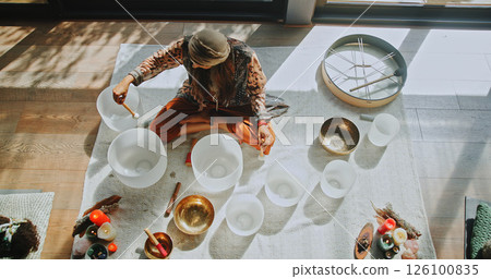Woman, singing bowl and sound on floor for therapy, frequency or peace with mindfulness at studio. Person, shaman and above with guide in class, crystal or zen for chakra balance for holistic healing 126100835