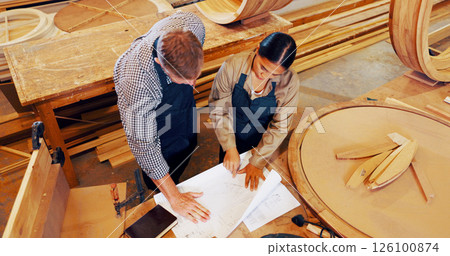 Man, woman and blueprint with wood at factory, above or review with mentor, training and construction material. People, floor plan and coach with timber, feedback or equipment at industrial warehouse Man, woman and blueprint with wood at factory, above or review with mentor, training and construction material. People, floor plan and coach with timber, feedback or equipment at industrial warehouse 126100874