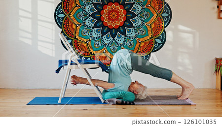Fitness, upside down or yoga and woman in studio with wall art for balance, spine or wellness routine. Chair, exercise or pilates and senior person in class with mandala symbol for holistic health 126101035