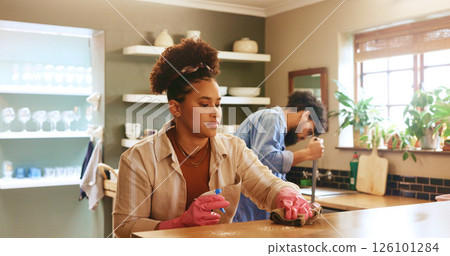 Woman, cloth and cleaning with spray in kitchen at home with partner, gloves or routine in morning. Couple, relationship and ppe with chemical for bacteria, germs and dirt with shine at apartment 126101284