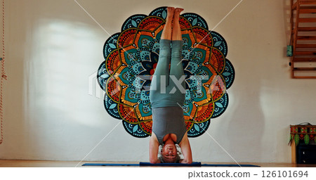 Balance, upside down or yoga and woman in studio with wall art for fitness or wellness routine. Exercise, headstand or pilates and senior person in class with mandala symbol for holistic health 126101694