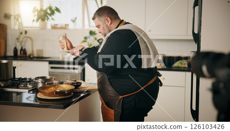 Man, chef and recording in kitchen with food, dinner or recipe online for content creation. Camera, cooking and influencer person with equipment for live streaming, diet advice and meal in home 126103426