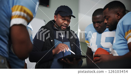 Tablet, coaching and football with team in locker room for game plan, sports strategy or defense formation. Touchdown tactics, match feedback and discussion with people and advice for training 126103454