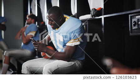 Athlete, football and man with phone in locker room for text message, mobile chat response and match break. Sports, player and relax with smartphone for social media scroll, online news or connection Athlete, football and man with phone in locker room for text message, mobile chat response and match break. Sports, player and relax with smartphone for social media scroll, online news or connection 126103623