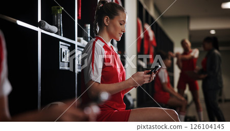Cellphone, woman and athlete in locker room for game, match or practice with scrolling on social media. Tech, relax and female soccer player with phone for networking on mobile app in changing area. 126104145